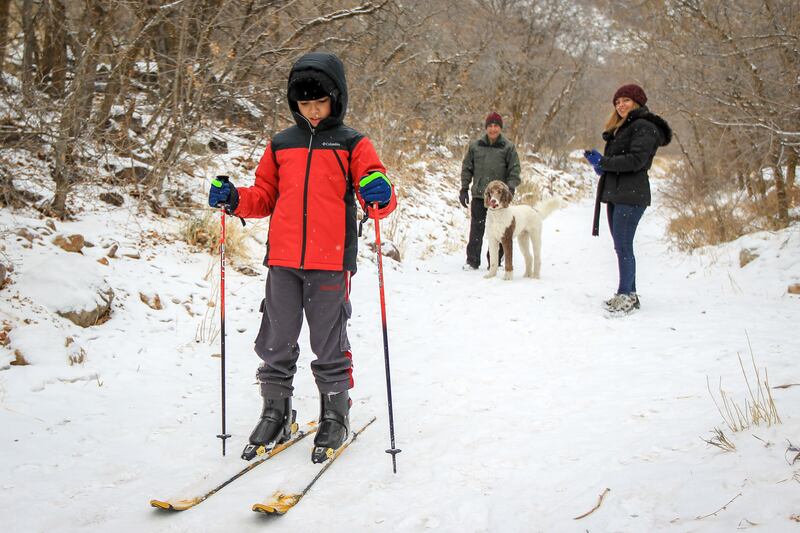Kousha Farang, who is from Iran and never seen snow before, skis down Neffs Canyon Trail after a fresh dusting of snow in Salt Lake on Saturday, Dec. 16, 2017, as Behrouz Farang and Aazadeh Farang, right, look on.