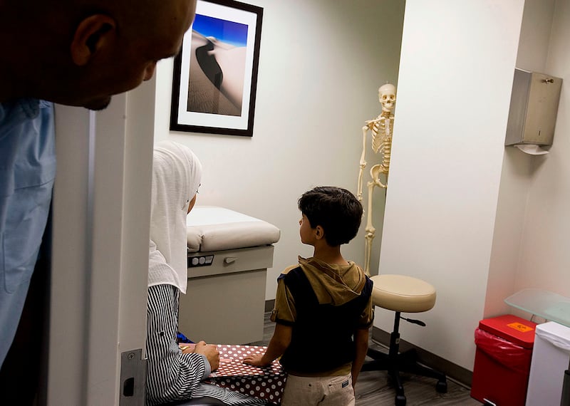Hussain Al Rumaid checks in on Baraa Huraideen and her son Eslam Hamad, as they wait for their medical screenings at St. Mark’s Hospital Family Medicine Center in Millcreek on June 21, 2017. Al Rumaid was the interpreter for the Hamads and the medical sta