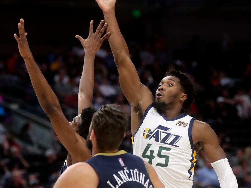 Utah Jazz guard Donovan Mitchell, wearing a white jersey, shoots over New Orleans Pelicans center Jonas Valanciunas