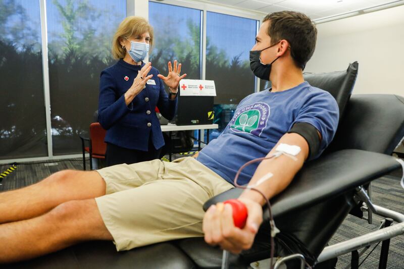 American Red Cross President and CEO Gail McGovern talks to BYU student while he donates blood on the Provo, Utah, campus.