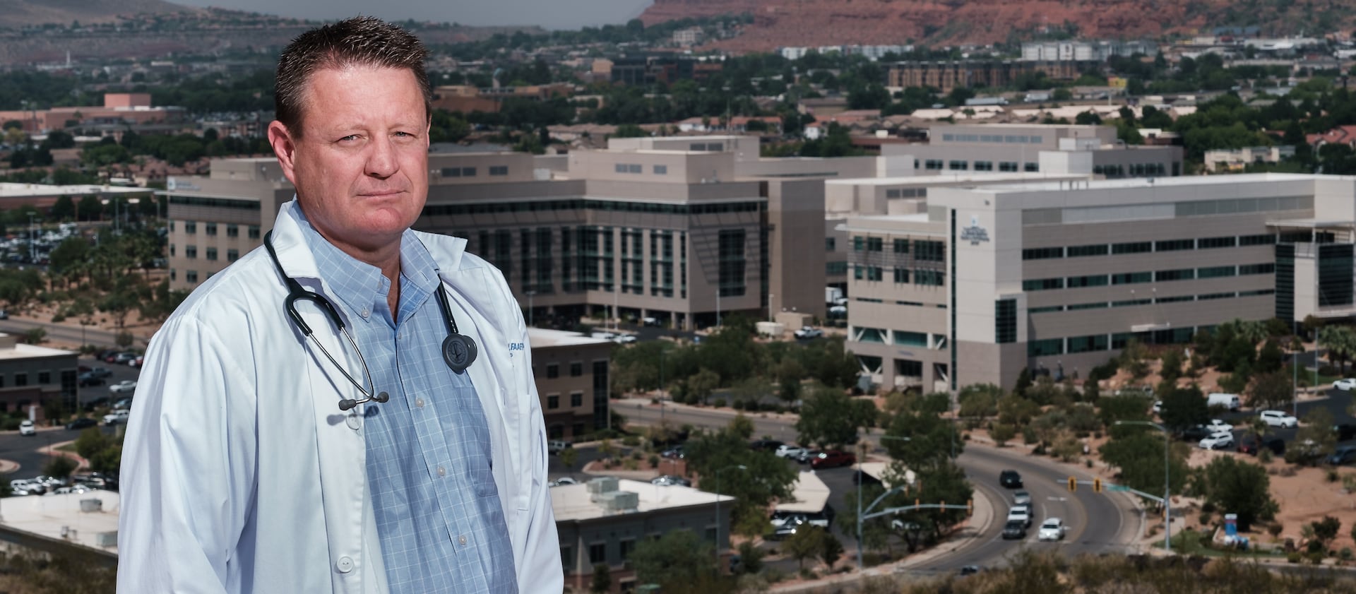Dr. David Grygla, hospitalist at a St. George hospital, poses for a portrait with the St. George skyline behind him.