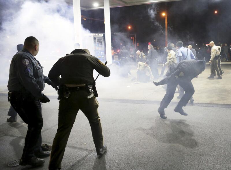 Police try to control a crowd Wednesday, Dec. 24, 2014, on the lot of a gas station following a shooting Tuesday in Berkeley, Mo. St. Louis County police say a man who pulled a gun and pointed it at an officer has been killed.