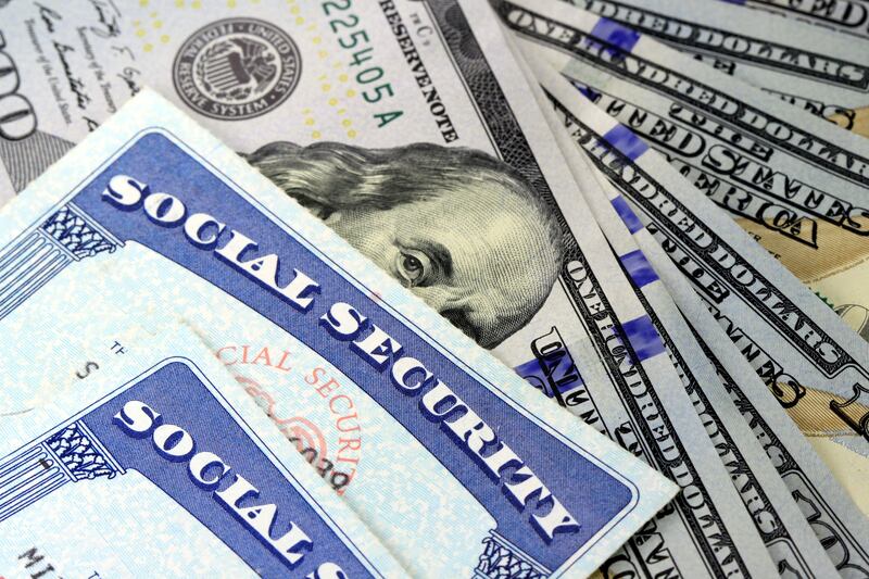 Social Security cards overlay hundred dollar bills.