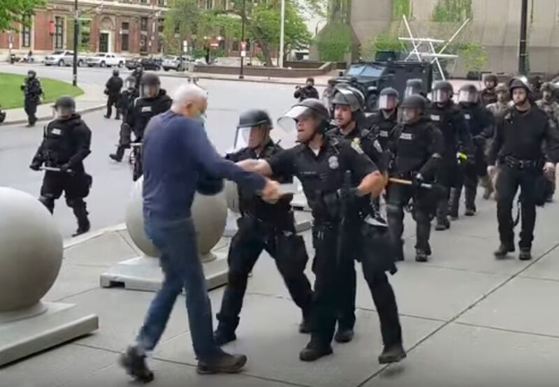 In this image from video provided by WBFO, a Buffalo police officer appears to shove a man who walked up to police Thursday, June 4, 2020, in Buffalo, N.Y. Video from WBFO shows the man appearing to hit his head on the pavement, with blood leaking out as officers walk past to clear Niagara Square.