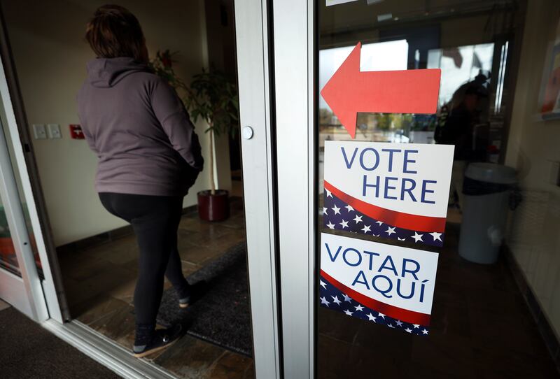 A woman walks past “Vote Here” signs at Taylorsville City Hall on Election Day in Taylorsville on Nov. 8, 2022.