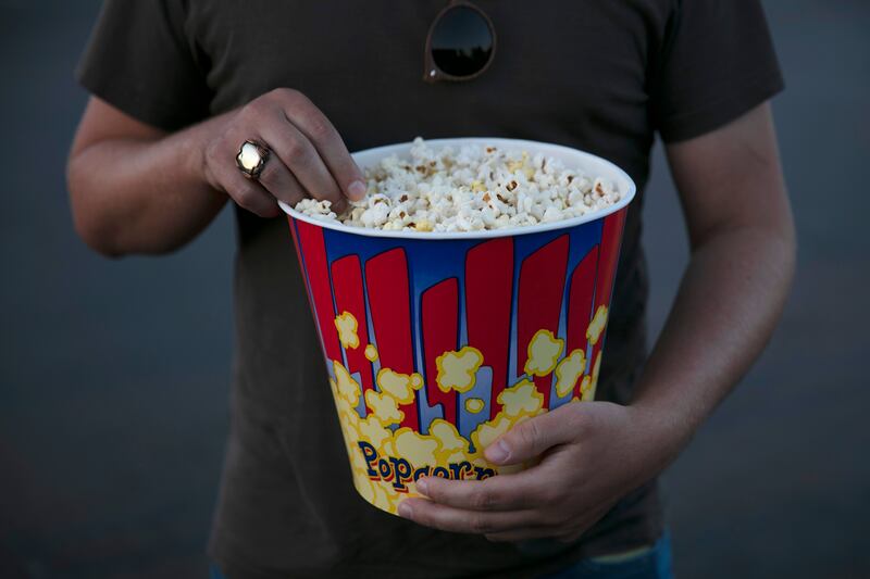 A moviegoer eats popcorn at Mission Tiki drive-in theater in Montclair, Calif.