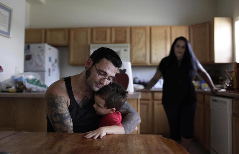 In this Monday, Aug. 1, 2011 photo, Bryon Widner hugs his 4-year-old son, Tyrson, at their home as his wife Julie watches. After getting married in 2006, the couple, former pillars of the white power movement (she as a member of the National Alliance, he