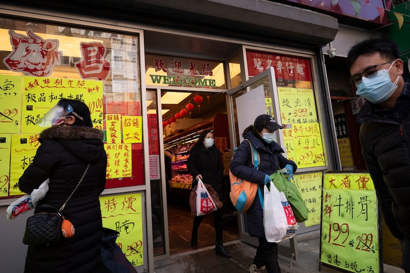 Shoppers leave a meat market, Monday, Feb. 8, 2021 in the Chinatown neighborhood of New York. Experts suggest opening up right now with low COVID-19 numbers might lead to a surge of cases from the new variants