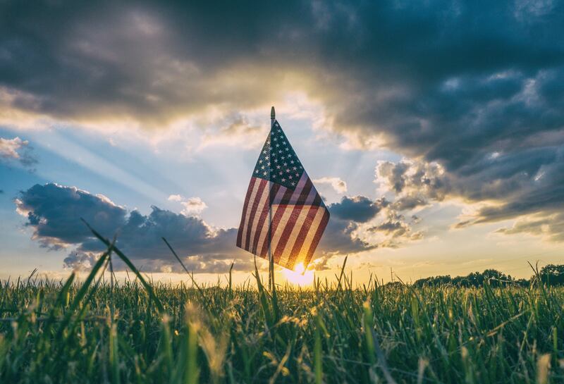 An American flag in a field at sunset.
