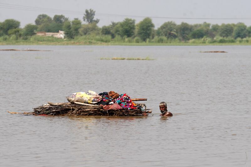 A displaced man transports usable belongings salvaged from his flood-hit home across a flooded area in the Shikarpur district of Sindh province, Pakistan.