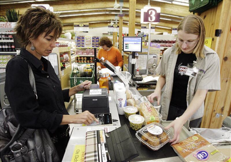 Kathy Sessions, left, pays with her card as Jenni Moore bags her groceries at Emigration Market in Salt Lake City.