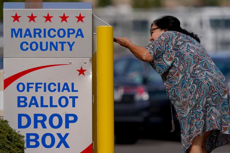 A voter drops off her ballot at a drop box in Mesa, Ariz.