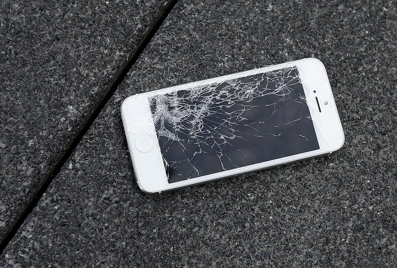 Cracked iPhone on asphalt.