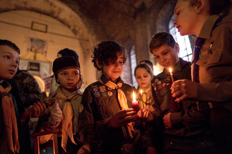 Members of Plast, a Ukrainian scouting organization, hold the Bethlehem Light of Peace during a Christmas church service.
