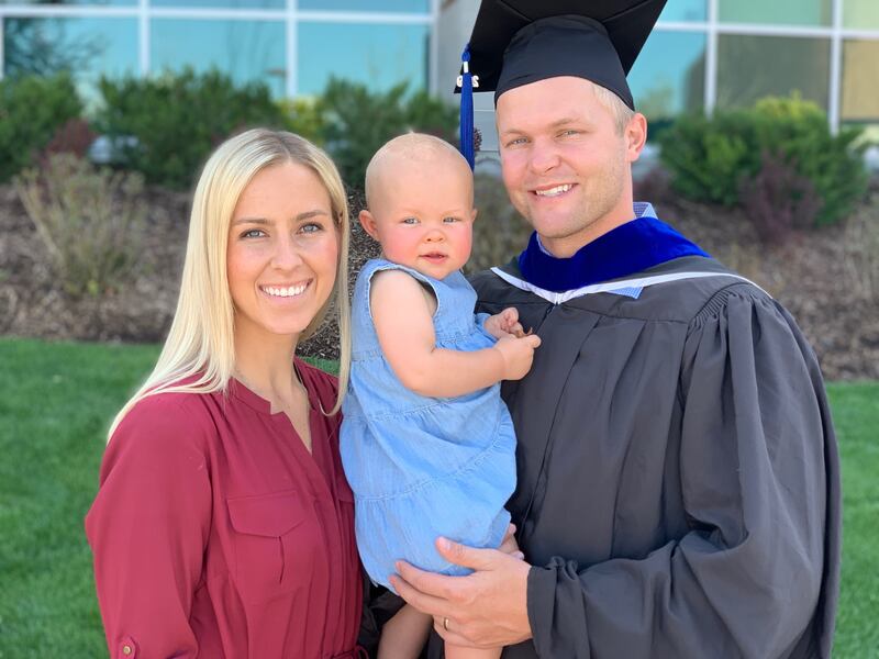 Adam Pulsipher poses at his graduation with his wife, Makenzi, and their daughter, Faith.