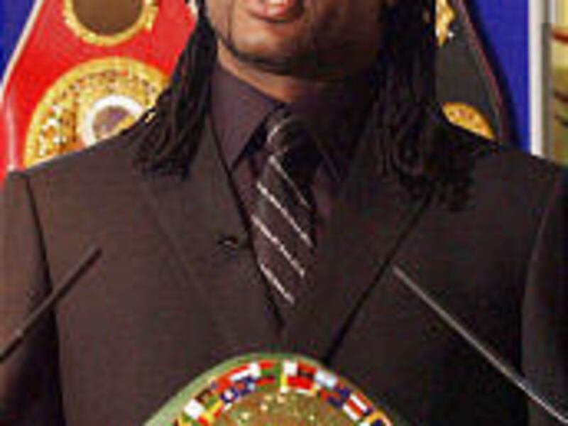 Lennox Lewis flashes his title belt while announcing his retirement.