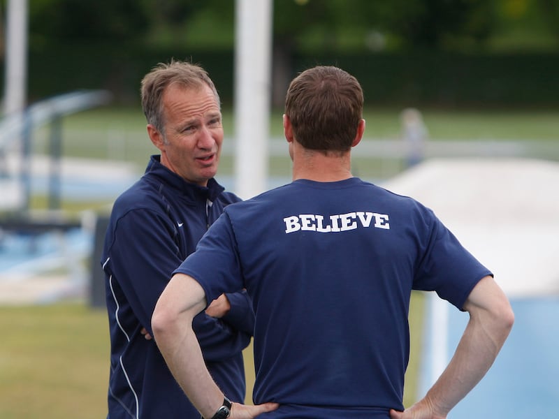 BYU track and field coach Ed Eyestone talks with an athlete who is wearing “BELIEVE” across the back of their shirt.