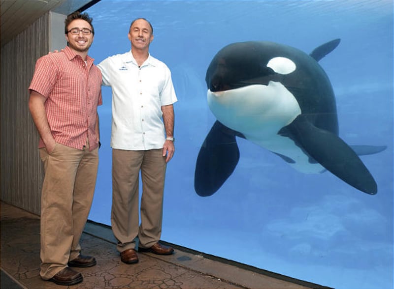 Chuck Tompkins, co-author of "Whale Done Parenting," stands with his son, Cody, left, and a whale at SeaWorld Orlando, December 7.