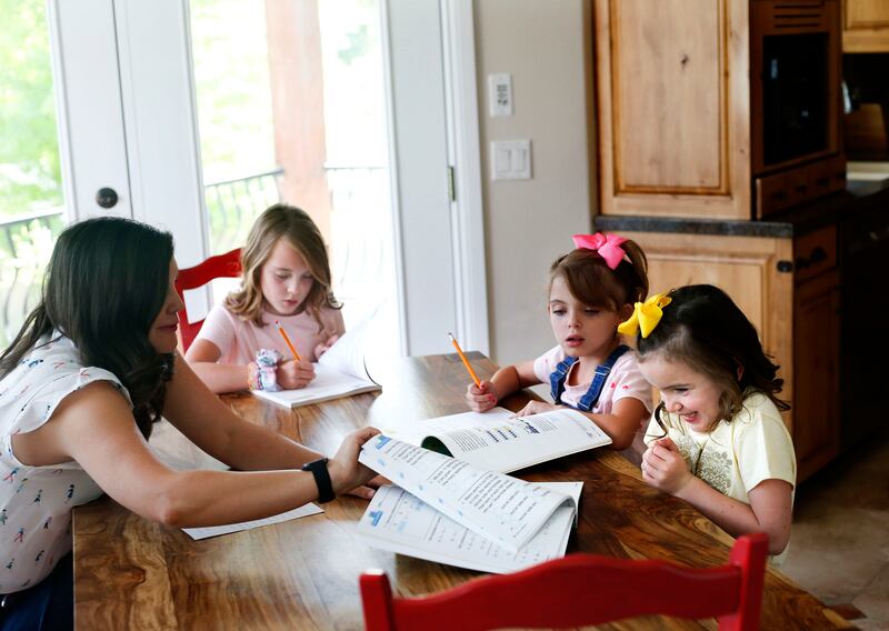 Vivian Seger, 6, pictured with her sisters, gets excited about getting a peek at her new math book at her South Jordan home.