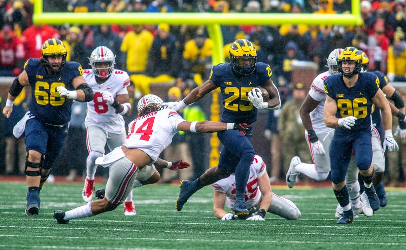 Michigan running back Hassan Haskins, wearing blue, breaks a tackle from Ohio State safety Ronnie Hickman