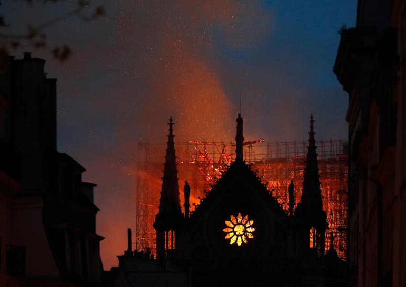 Flames and smoke rise from Notre Dame cathedral as it burns in Paris, Monday, April 15, 2019. Massive plumes of yellow brown smoke is filling the air above Notre Dame Cathedral and ash is falling on tourists and others around the island that marks the cen