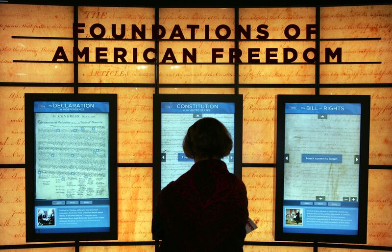 A visitor looks at a copy of the U.S. Constitution set between the Bill of Rights and the Declaration of Independence.