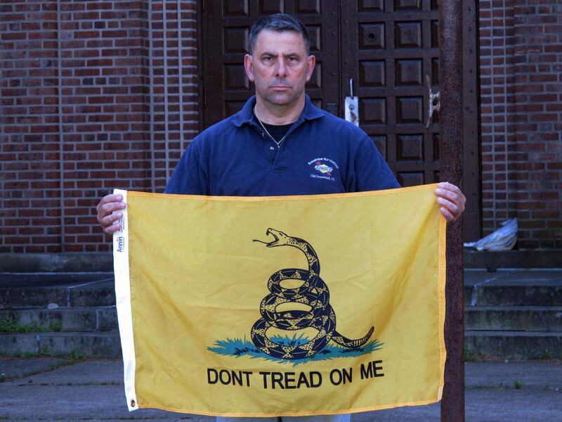 In this April 26, 2013 file photo, Peter Parente, president of the United Veterans Memorial and Patriotic Association, holds a Gadsden flag outside an armory in New Rochelle, N.Y. In a lawsuit filed in federal court, the veterans who put the flag up say t