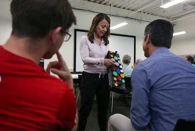 Neuroworx co-founder Jan Black, center, shows James Gardner, right, and Marc Rosello an adaptive use game controller that allows people without fingers to play a video game at the Sandy facility on Thursday, July 11, 2019.