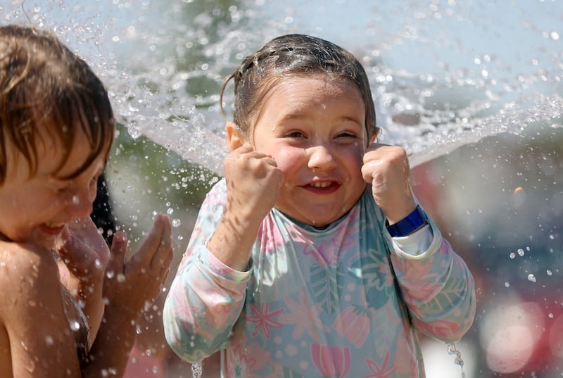 Samson Maurer and Mora Carter react as a fountain sprays them at the splash pad in Draper on Wednesday, July 20, 2022.
