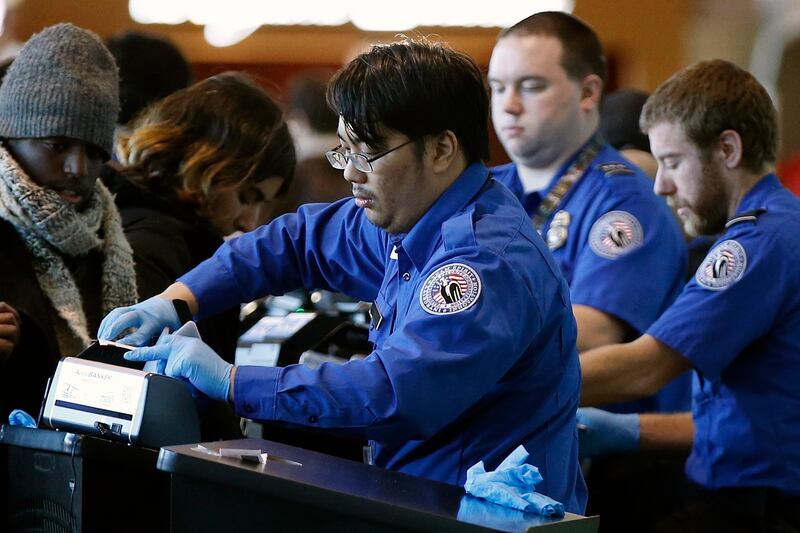 In this Dec. 23, 2018 file photo, Transportation Security Administration officers check boarding passes and identification at Logan International Airport in Boston.