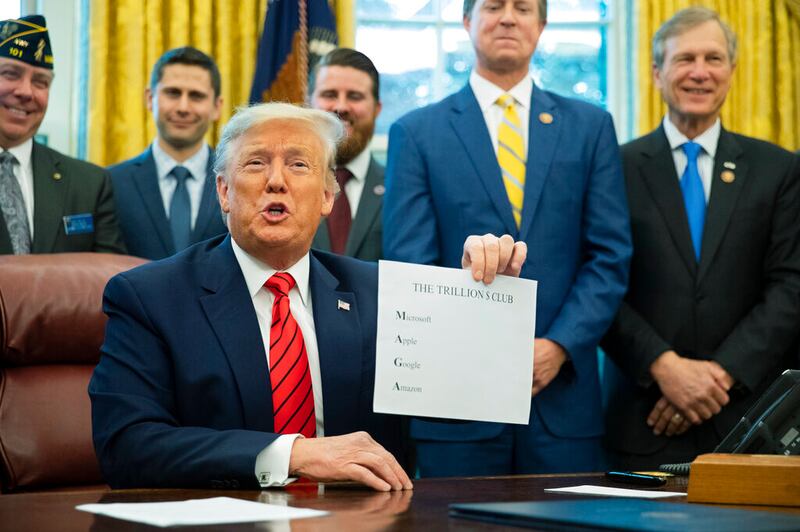 President Donald Trump shows a paper in Washington.