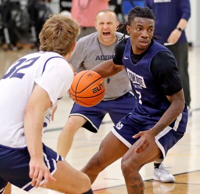 Senior guard Kolby King, a transfer from Butler, handles the ball while Utah State associate head coach Eric Haunt encourages Utah transfer Zach Keller (32) to lock down on defense during the Aggies’ practice Tuesday morning at the Wayne Estes Center in Logan.
