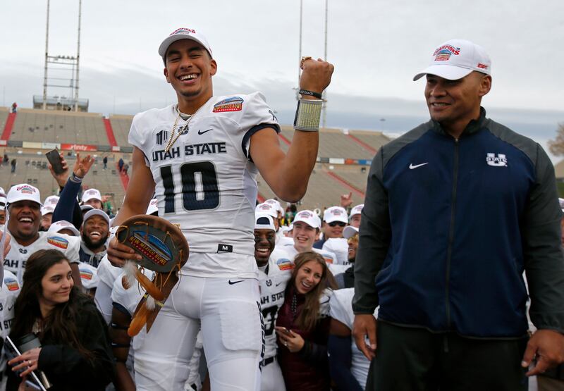 Utah State quarterback Jordan Love (10) celebrates after being named the Outstanding Offensive Player as interim head coach Frank Maile looks on, following the New Mexico Bowl NCAA college football game in Albuquerque, N.M., Saturday, Dec. 15, 2018. Utah