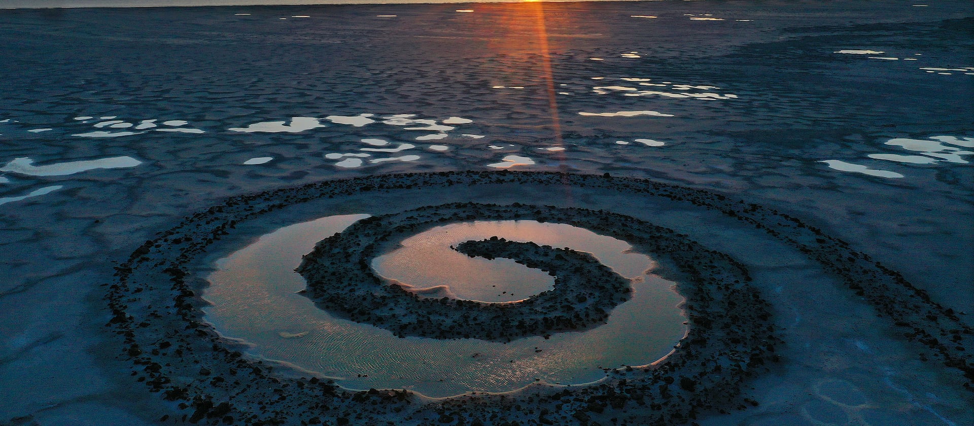 The sun sets on the Spiral Jetty on the Great Salt Lake on Thursday, March 16, 2023.