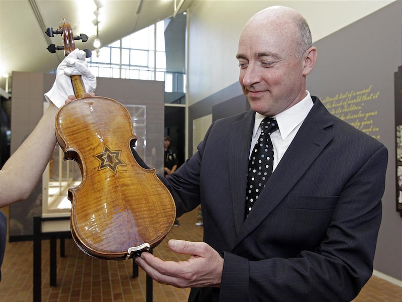 In a Monday, April 9, 2012 photo, David Russell, distinguished professor of violin at UNC Charlotte, examines one of the violins on display at the Violins of Hope exhibit at UNC Charlotte in Charlotte, N.C. Brosvik launched the Violins of Hope initiative in Nashville.