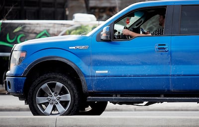 A driver holds his cellphone up as he drives on State Street in Salt Lake City on Monday, Feb. 25, 2019.