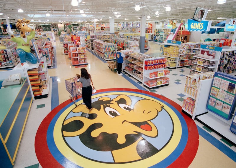 In this July 30, 1996, file photo, a woman pushes a shopping cart over a graphic of Toys R Us mascot Geoffrey the giraffe at the Toys R Us store in Raritan, N.J.