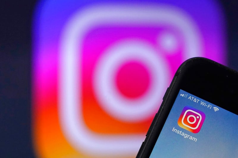 An Instagram logo is shown on an iPhone screen.