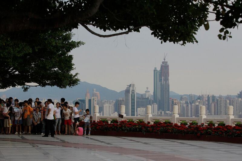 In this Sept. 5, 2010, file photo, tourists visit a park with a background view of Shenzhen city, Guangdong Province, Southern China.