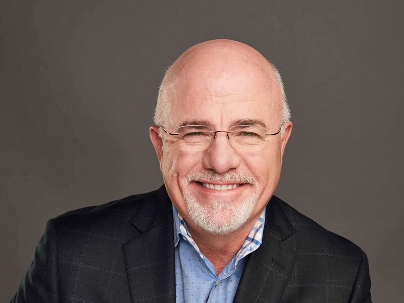 Dave Ramsey poses for a picture with a grey backdrop.