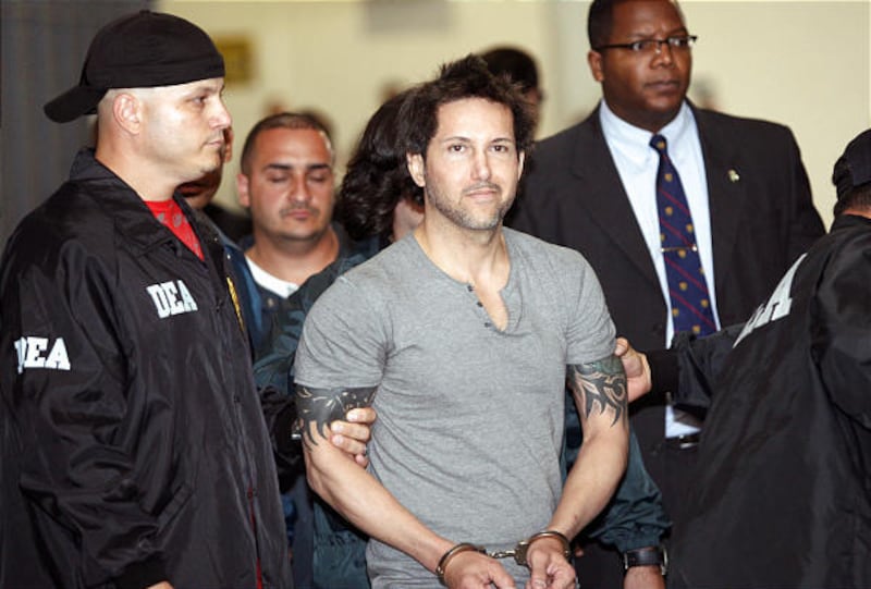 Jose Figueroa Agosto is escorted handcuffed by DEA agents after his arrest in San Juan, Saturday.