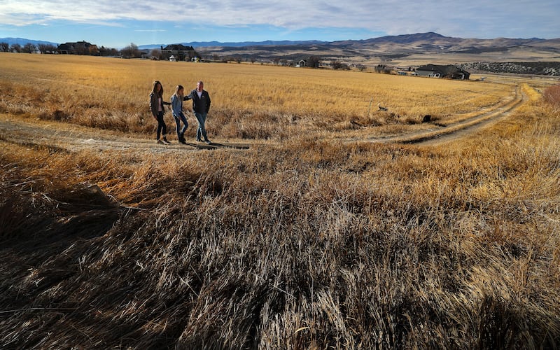 Utah Governor, Spencer Cox, walks with his wife, Abby, and daughter, Emma Kate, on their farmland in Fairview, Utah.
