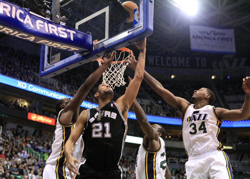 San Antonio Spurs center Tim Duncan (21) attempts a shot while defended by Utah Jazz center Al Jefferson, left, forwards Paul Millsap, second from right and C.J. Miles (34) during the first half on a NBA basketball game, Monday, Feb. 20, 2012, in Salt Lak