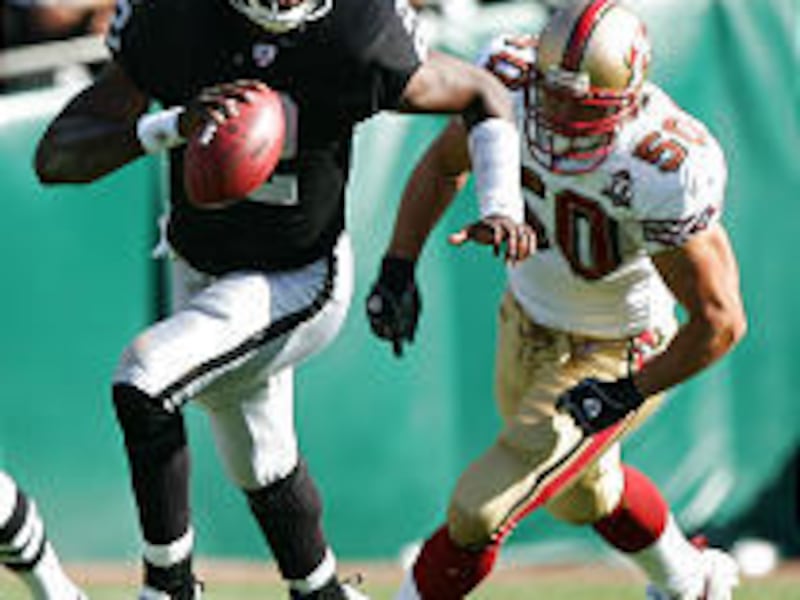 Quarterback Aaron Brooks of the Oakland Raiders runs with the ball Sunday as Derek Smith of the San Francisco 49ers pursues.