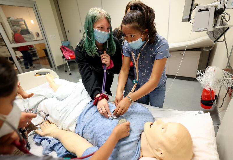 Students Emiry Ozmore and Layney Spencer listen to the computer simulated heartbeat of a medical mannequin.