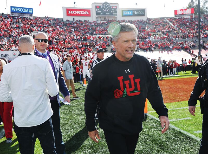 Utah Utes head coach Kyle Whittingham, wearing black, walks onto the field