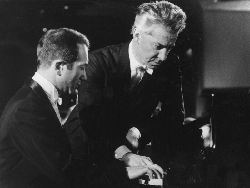 FILE This is a 1976 file photo of pianist Alexis Weissenberg. left, and Austrian conductor Herbert von Karajan , as they go over a part at the grand piano in West Berlin. Bulgarian-born pianist Alexis Weissenberg, whose love of music from the age of 3 s