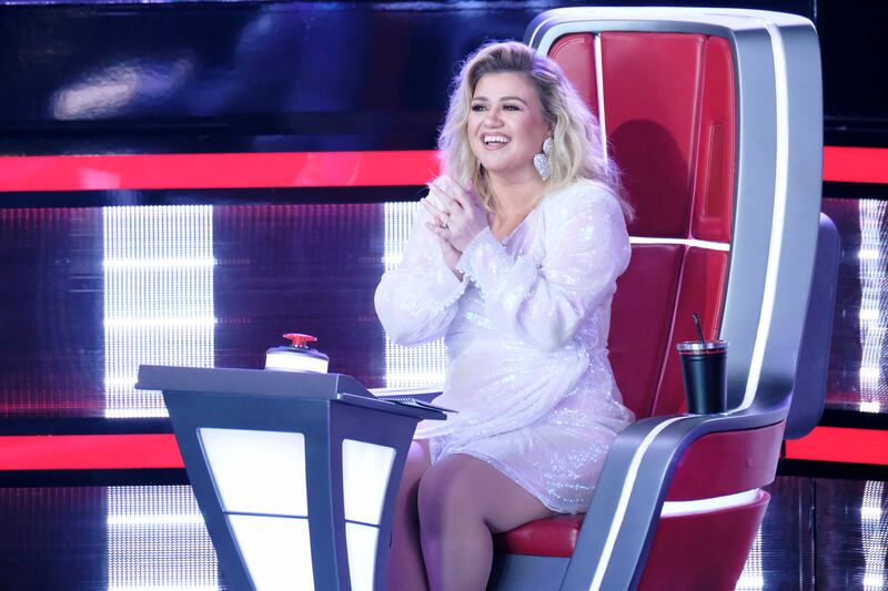 “The Voice” judge Kelly Clarkson sits in her judges chair smiling after a performance on the show.