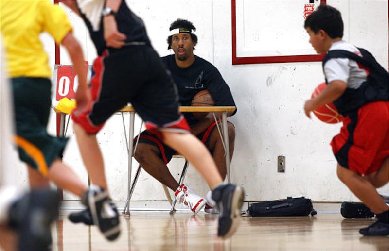 Former Utah Ute All-American Andre Miller keeps score and watches the kids participate at the Ute basketball camp.