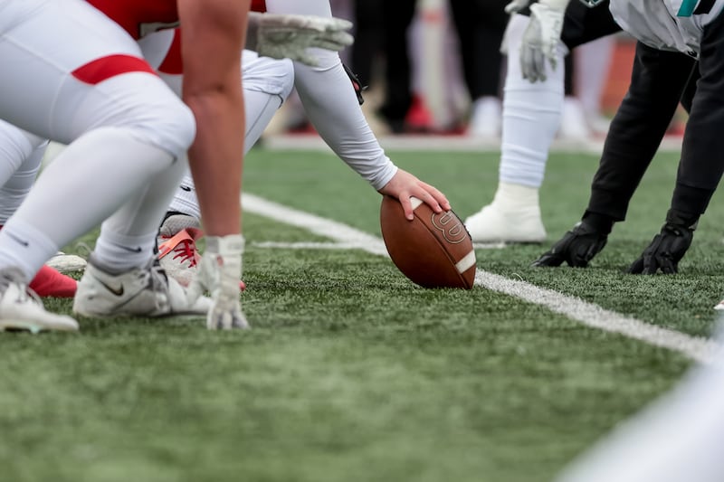 Football players line up as a football is about to be snapped during a high school football game.